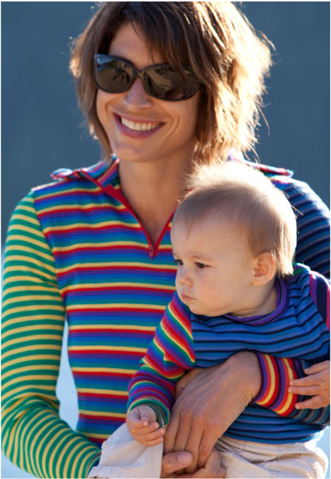 Thermal are worn by a lady holding a baby. Crew top thermals are brightly colored stripes, greens, blues and reds